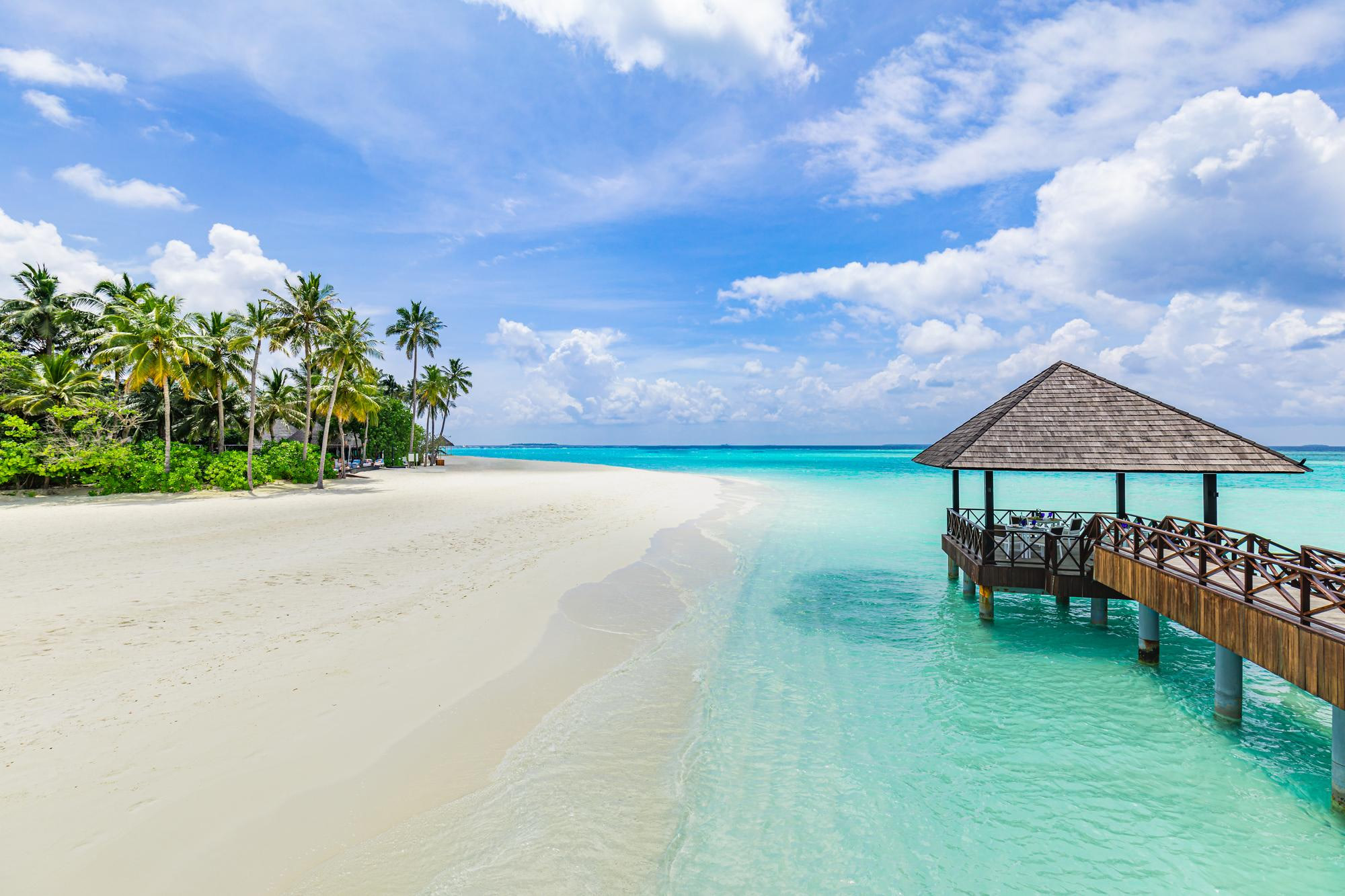 White beach with a wooden jetty and gazebo over turquoise water